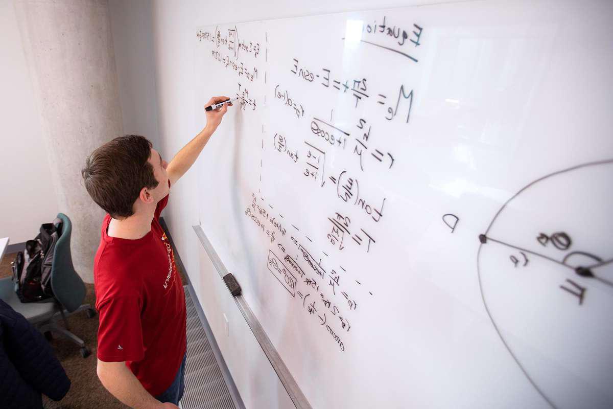 一个学生在白板上写方程式