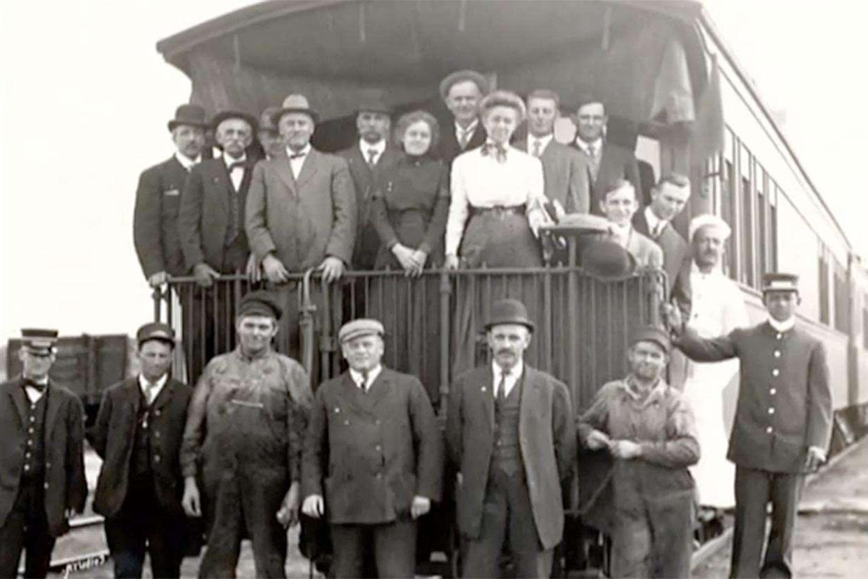 早期旅行扩展组在火车车尾摆姿势的黑白照片存档